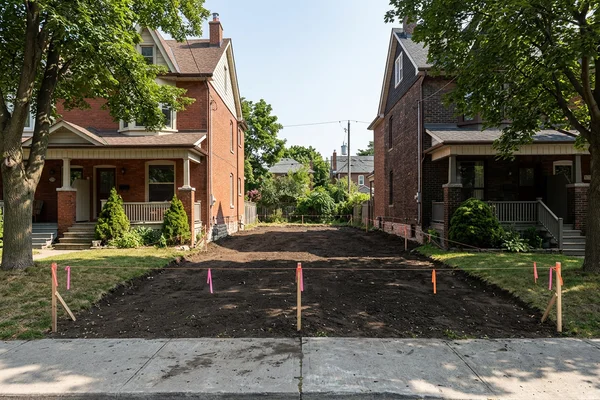 Empty infill lot with survey stakes marking setbacks